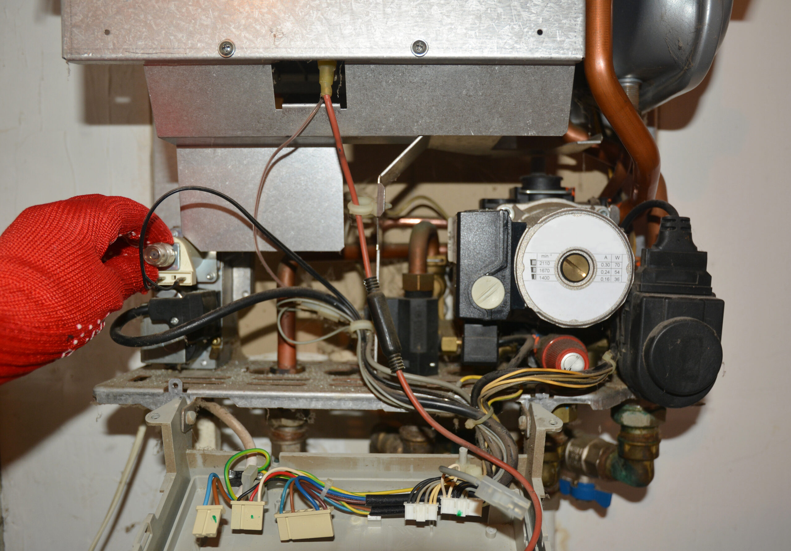 Technician in red gloves repairing a boiler